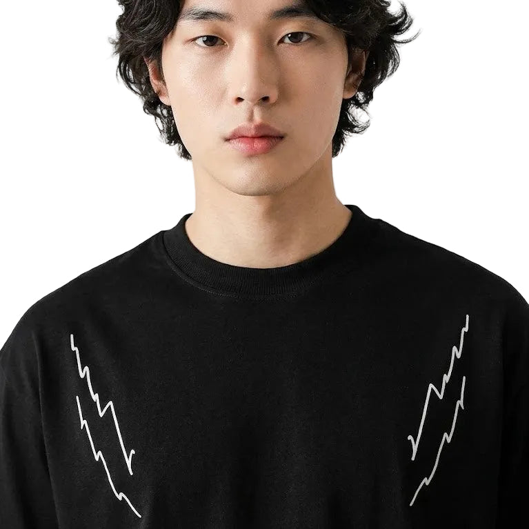 Person wearing a black sweater with white designs on a plain background