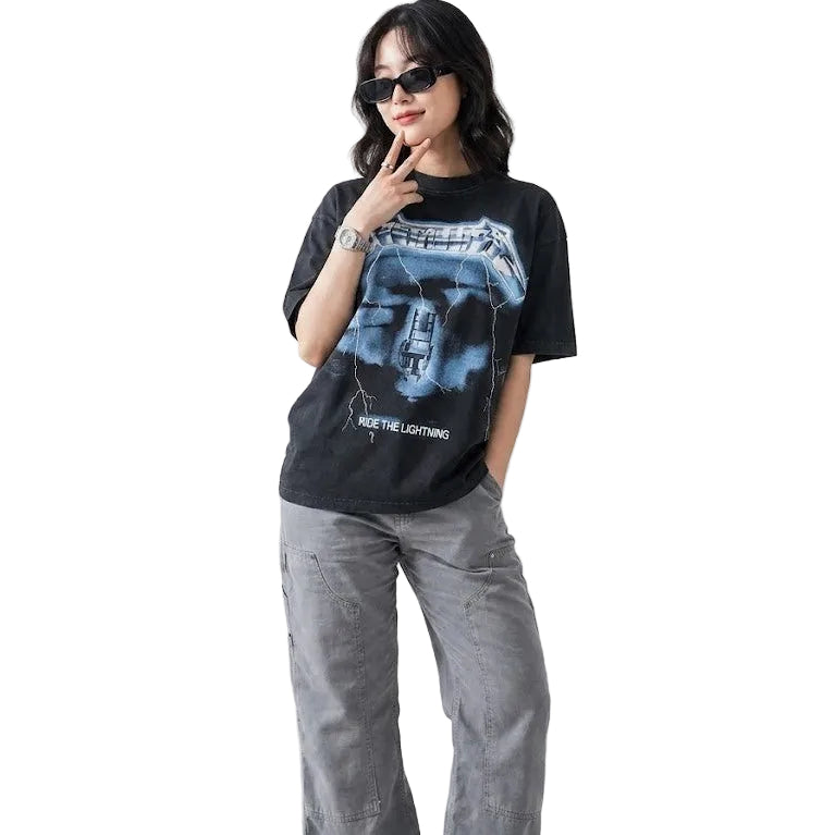 Person wearing a black t-shirt with a graphic design and gray pants on a white background