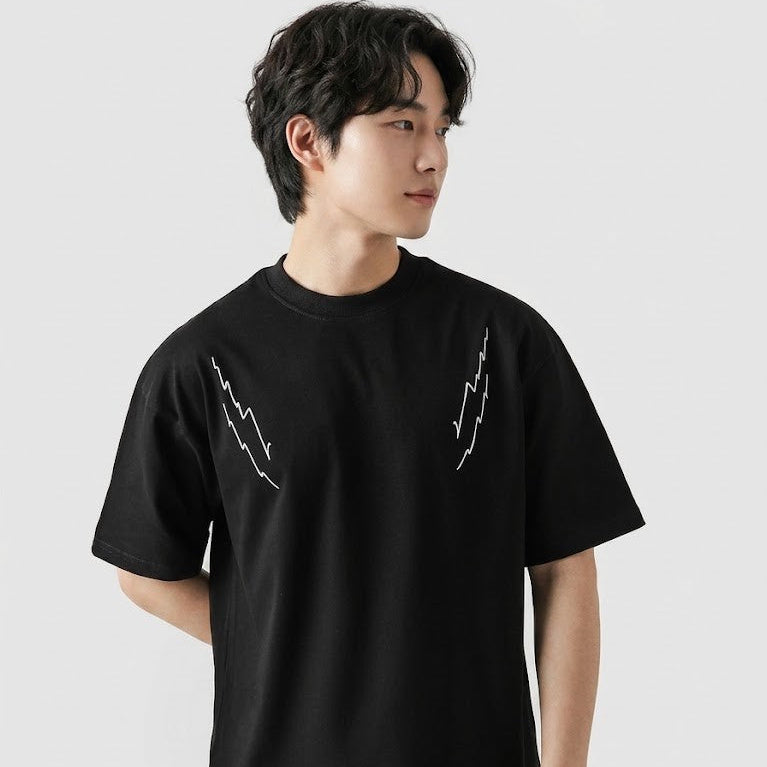 Person wearing a black t-shirt with white graphics on a plain background