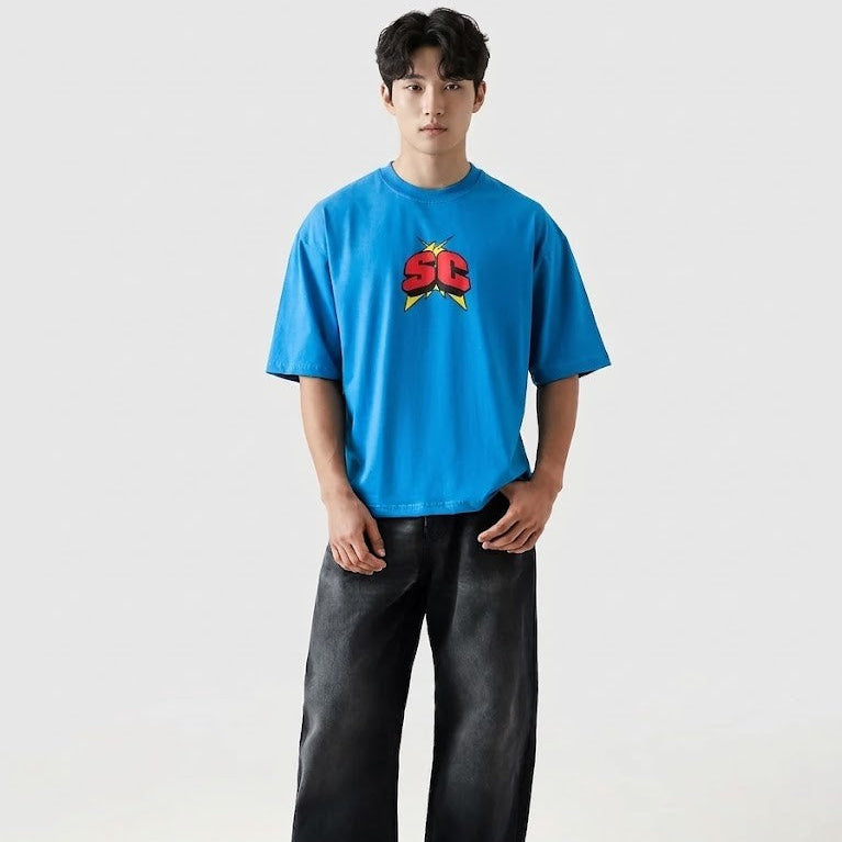 Person wearing a blue t-shirt with a logo and dark pants on a white background