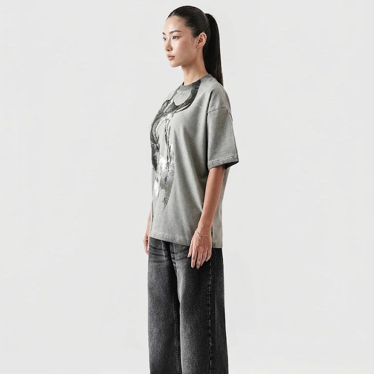 Person wearing a gray t-shirt with a graphic design and black pants on a white background
