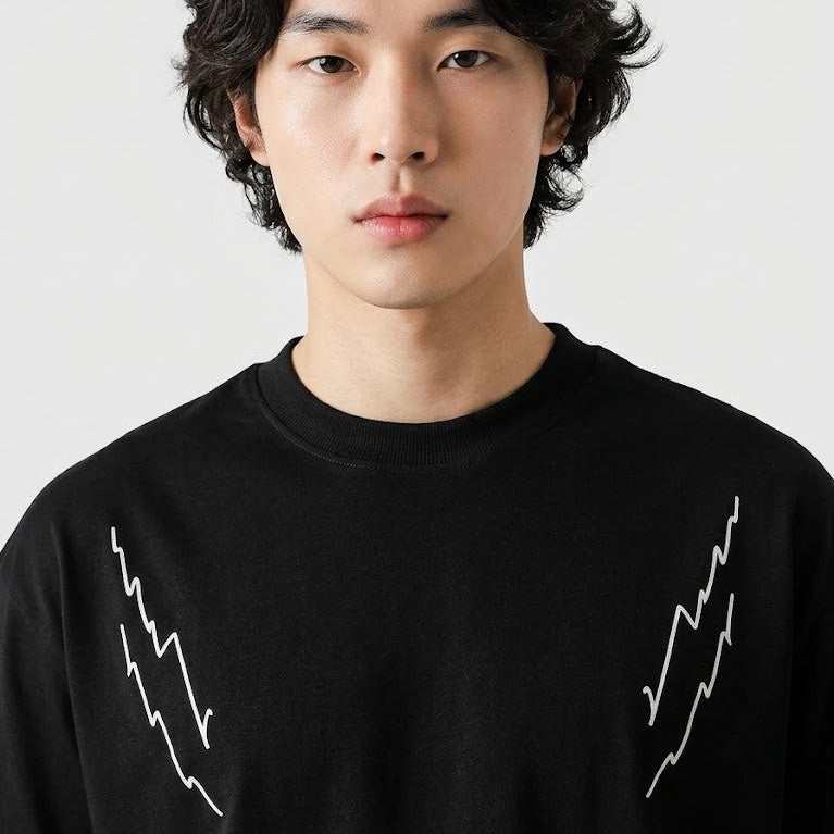 Person wearing a black sweater with white designs on a plain background