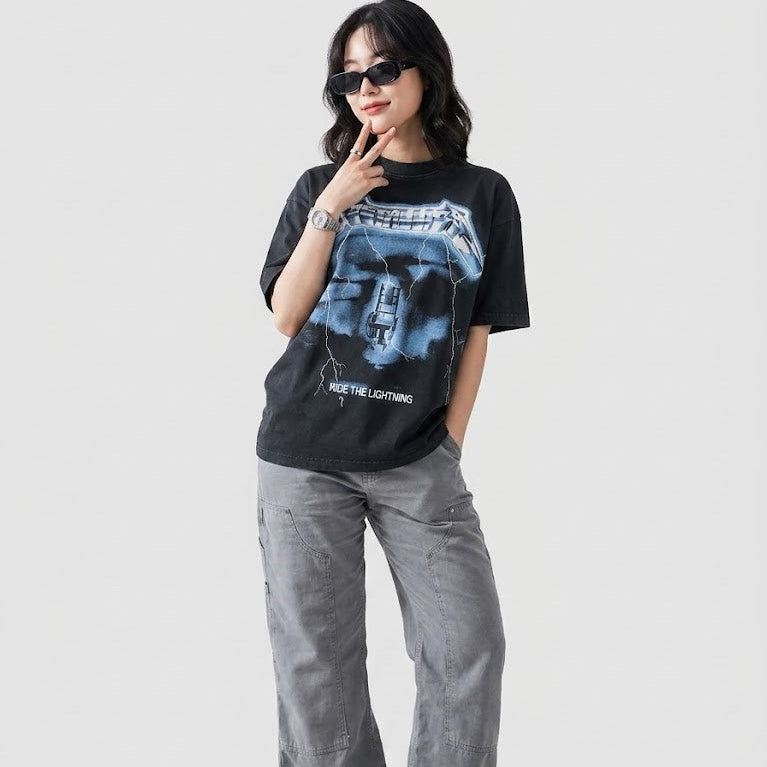 Person wearing a black t-shirt with a graphic design and gray pants on a white background