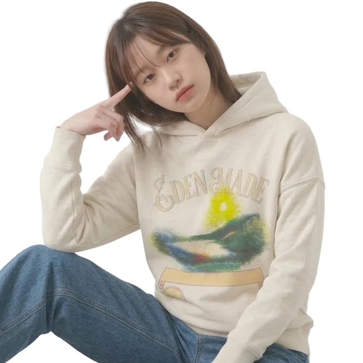 Person wearing a beige hoodie with a colorful design, sitting on a concrete bench.