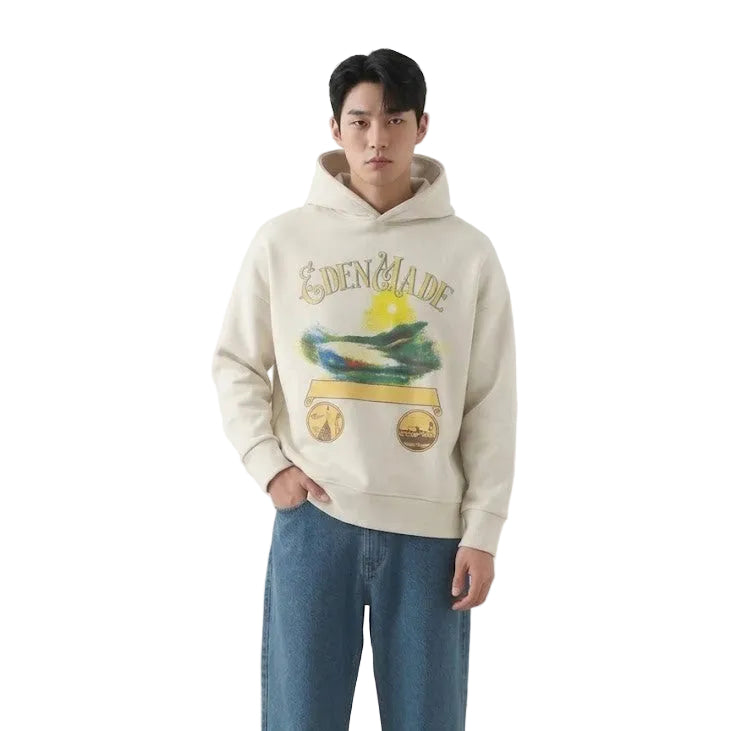 Person wearing a beige hoodie with graphic design and blue jeans on a plain background