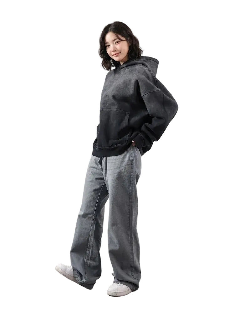 Person wearing a dark hoodie and light gray pants against a white background