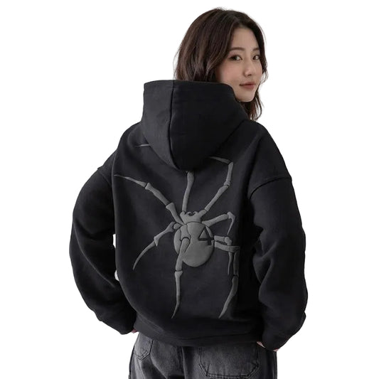 Person wearing a black hoodie with a spider design on the back against a plain background