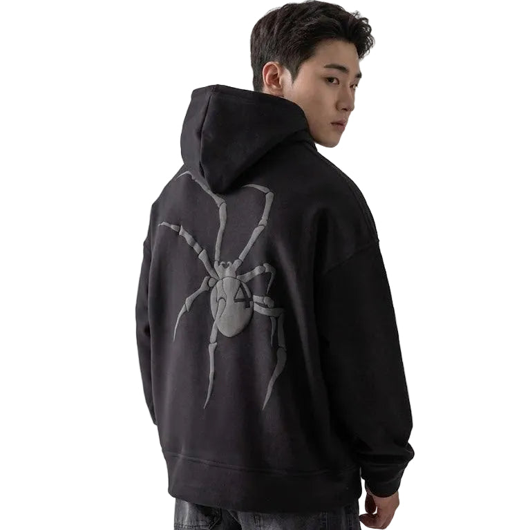 Person wearing a black hoodie with a spider graphic on the back against a white background