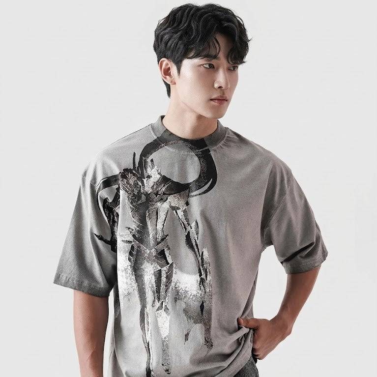 Person wearing a gray t-shirt with a graphic design on a plain background