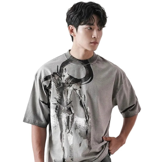Person wearing a gray t-shirt with a graphic design on a plain background