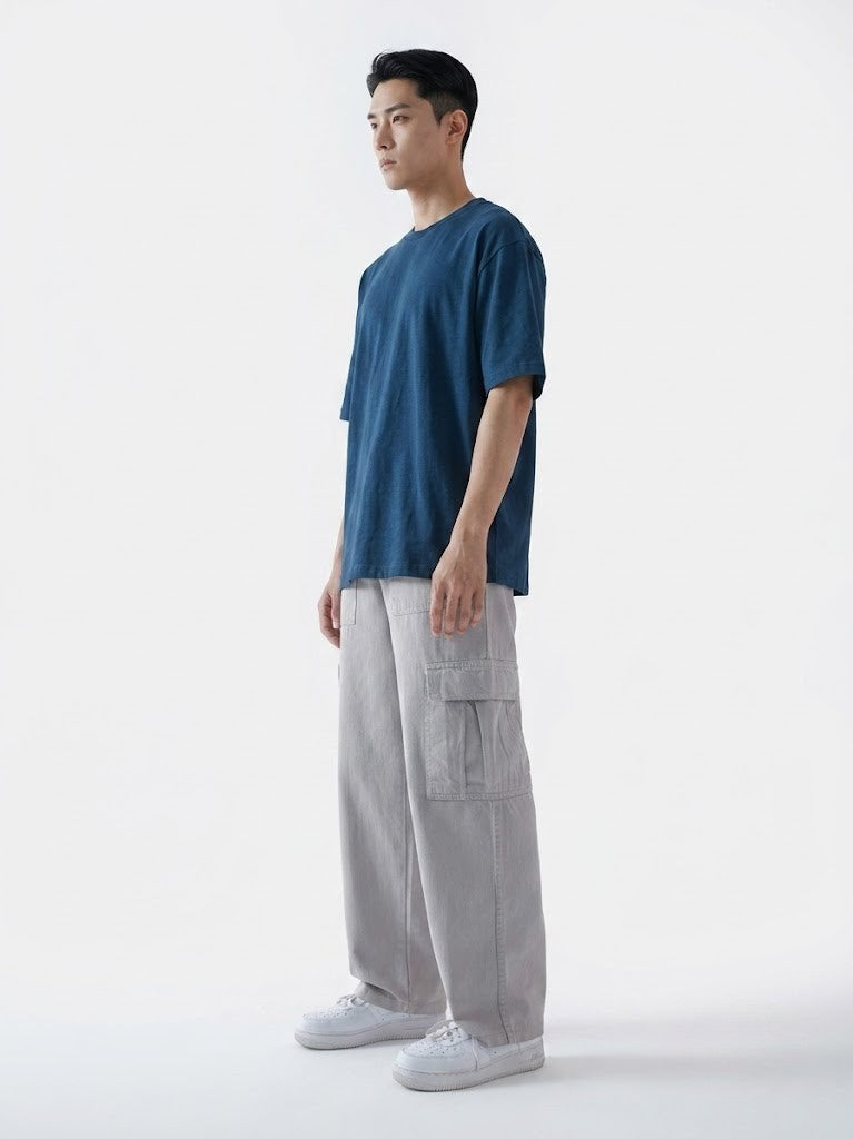 Man wearing a blue t-shirt and gray cargo pants on a white background