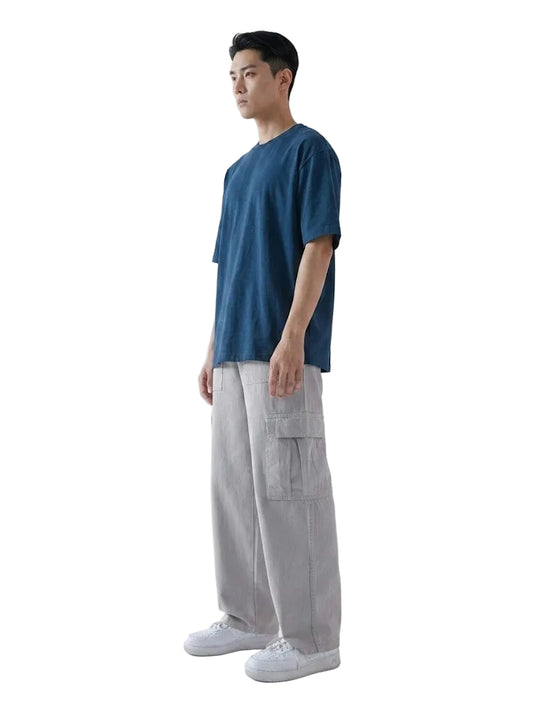 Man wearing a blue t-shirt and gray cargo pants on a white background