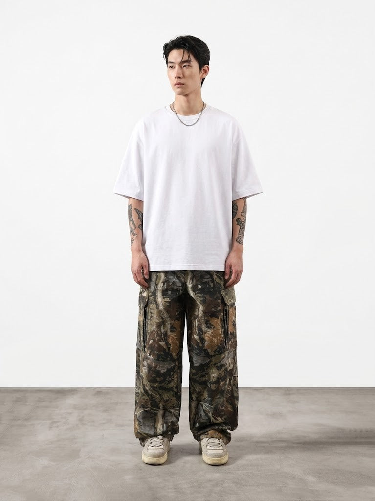 Person wearing a white t-shirt and camouflage pants on a plain background