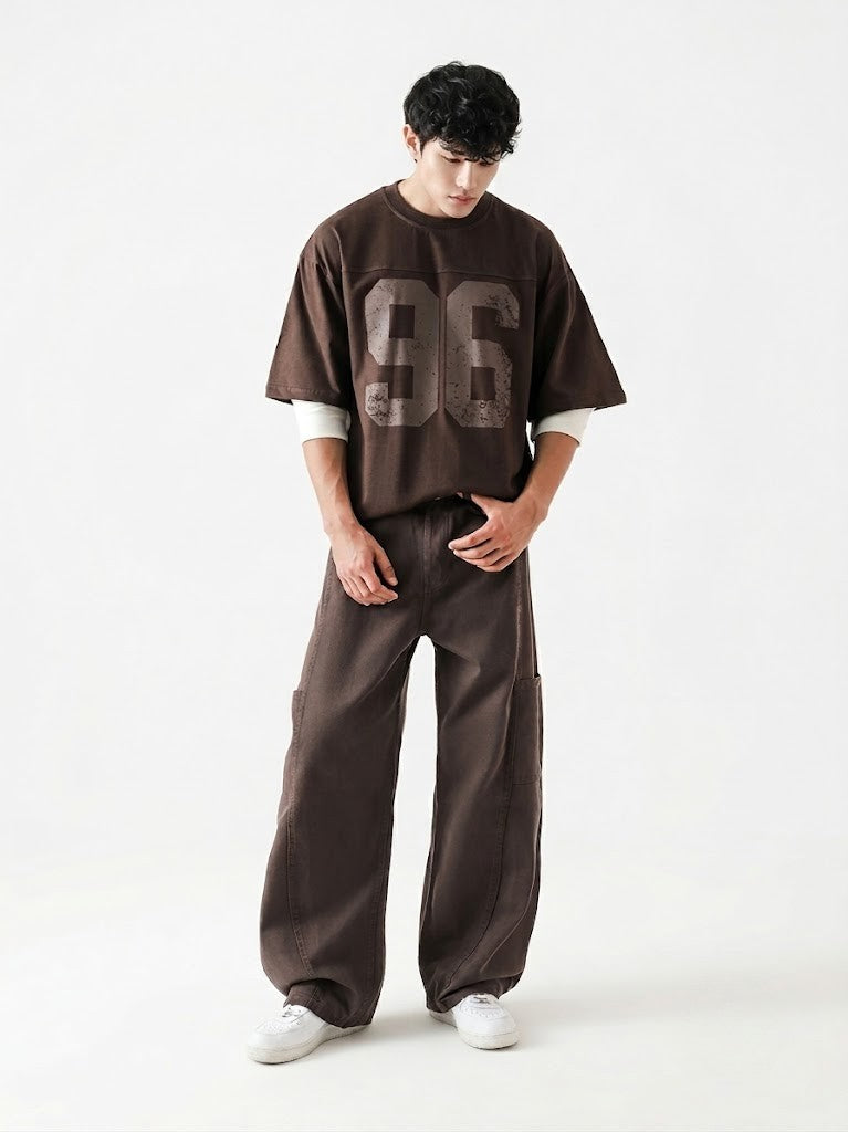 Person wearing a brown oversized t-shirt with '96' printed on it and matching pants on a white background