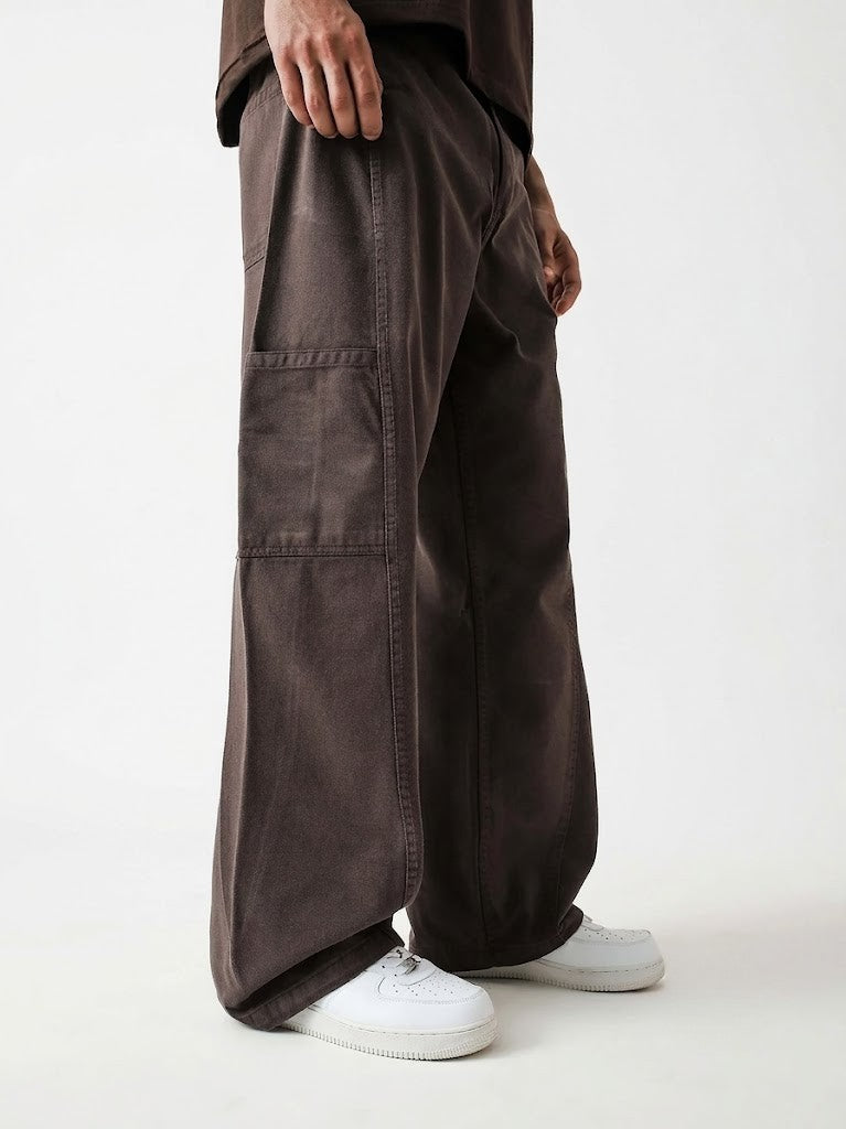 Person wearing brown wide-leg pants and white sneakers on a white background